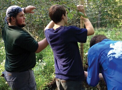 Bryce Dupes (left) works to install deer fencing at Miller Preserve.