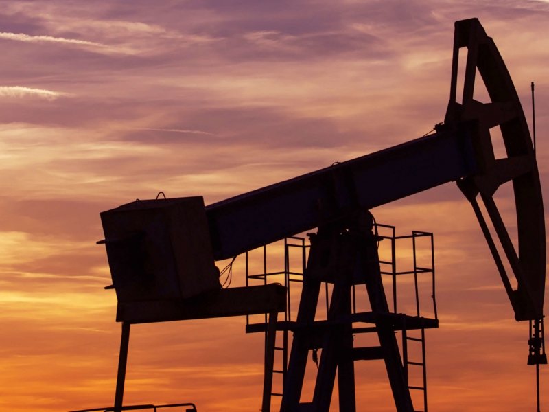 Operating oil and gas well profiled on sunset sky Operating oil and gas well profiled on sunset sky